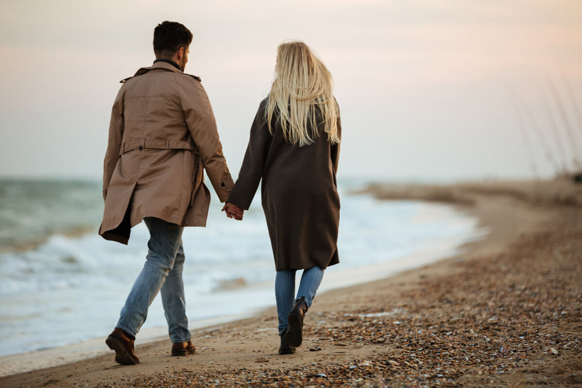 Couple walking in the beach in a cold cloudy day